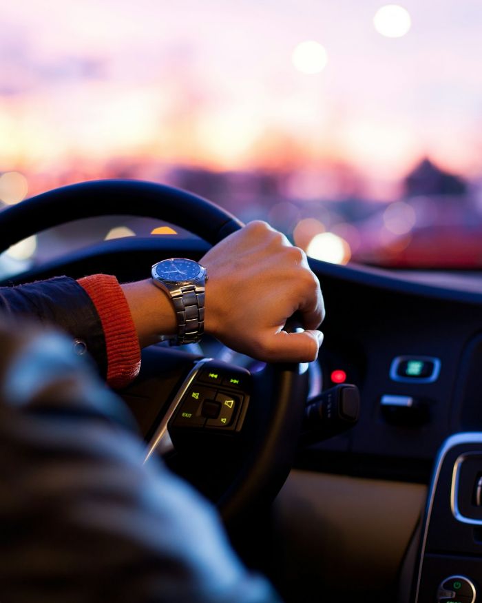 Driver's hands on the wheel of a car at dusk