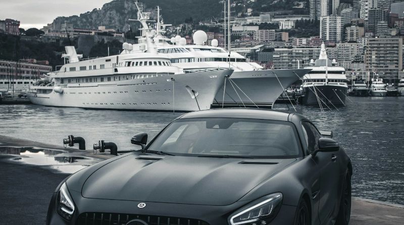 Superyachts moored in Monaco harbour behind a black sports car